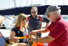 A senior sailing instructor is briefing a crew about the safety equipment.