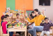 Teacher with preschool students having fun while finger painting at class